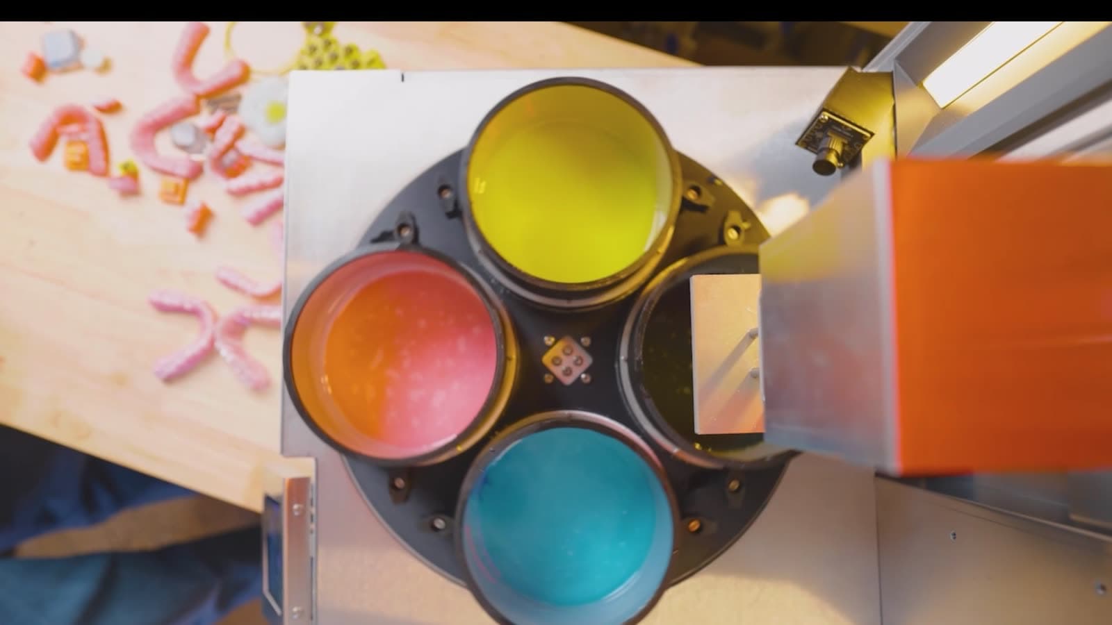 Top-down view of a four-vat material carousel holding yellow, magenta, cyan, and black resins.